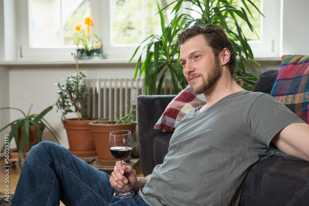 Thoughtful mid adult man drinking red wine in living room, Munich, Bavaria, Germany Thoughtful mid adult man drinking red wine in living room, Munich, Bavaria, Germany