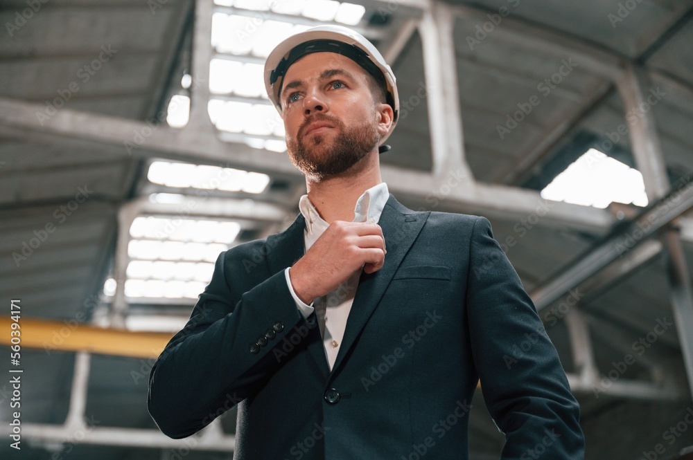 Adjusts the collar. Manager in black formal wear at the factory Adjusts the collar. Manager in black formal wear at the factory