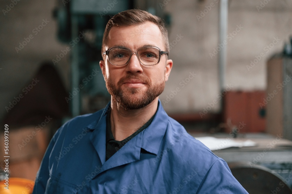 Portrait of factory worker that is in blue uniform indoors Portrait of factory worker that is in blue uniform indoors