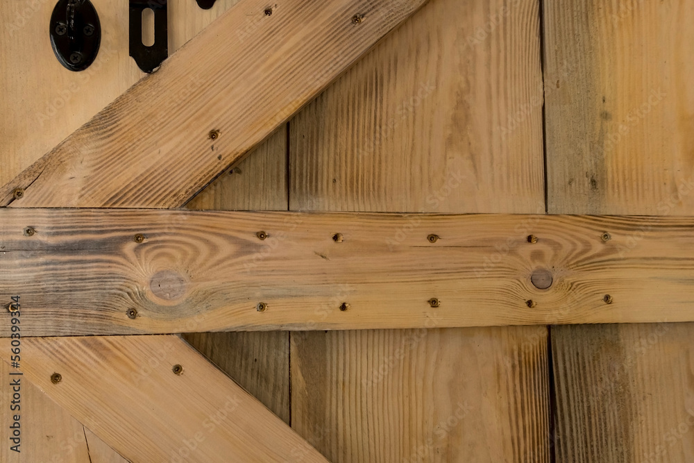 Fototapeta premium Nowo wykonane drzwi z drewnianych desek w stylu vintage . drzwi z czarną , stalową zasuwką .