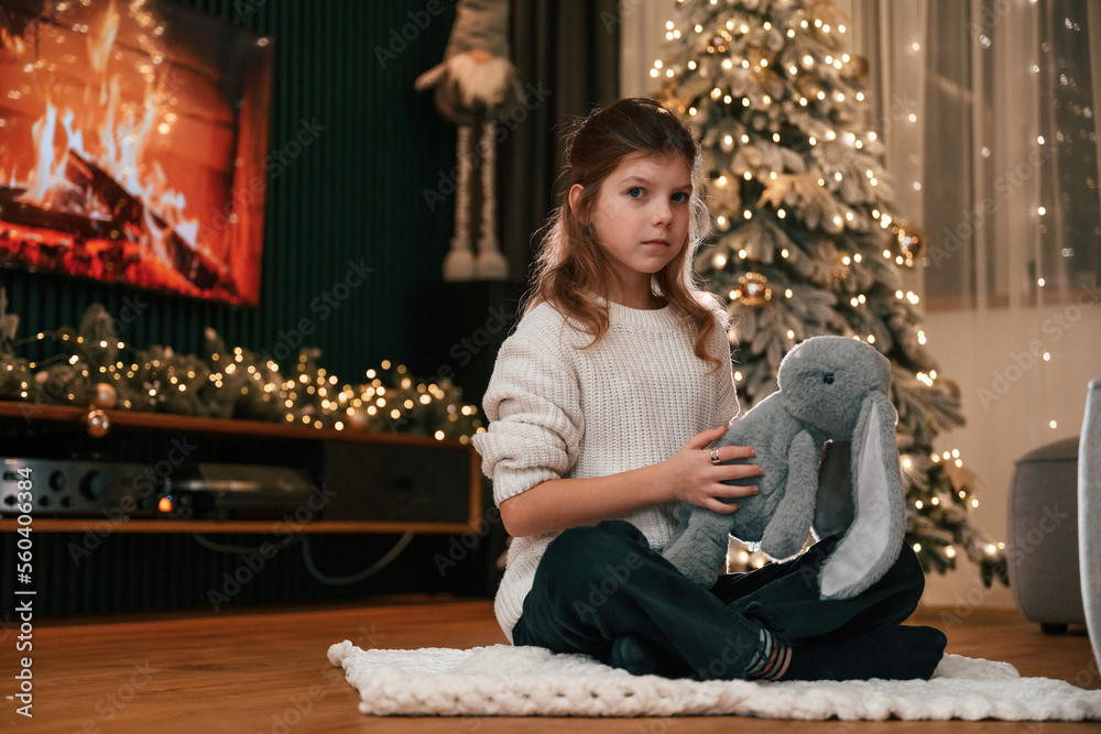 Holding toy in hands. Portrait of little girl that is at home celebrating new year Holding toy in hands. Portrait of little girl that is at home celebrating new year