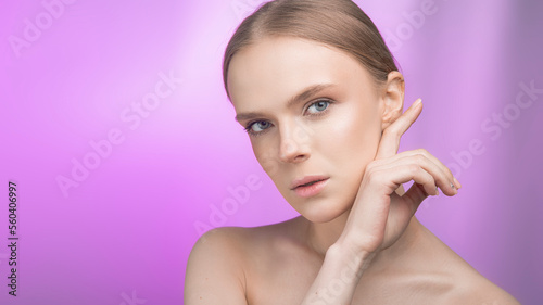 Beauty and skin care. Happy woman with fresh radiant  moisturized skin  standing with bare shoulders  with light makeup and natural skin on a pink background.