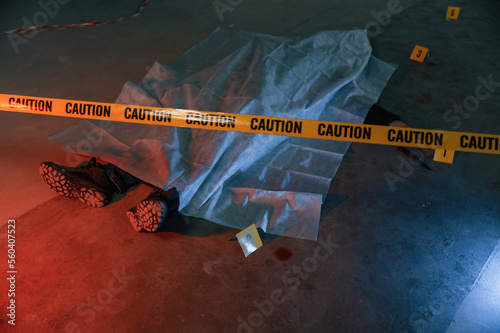 Knife and blood. Dead body of a man is on the ground, covered in white cloth. Conception of murder, homicide