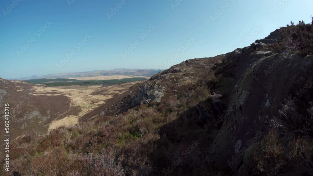 A man relaxing in the shade of a rock in the mountains A man relaxing in the shade of a rock in the mountains