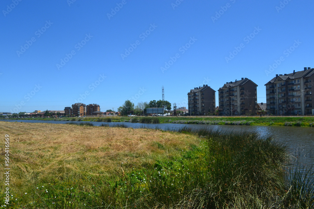 a river and some green areas near an urbanization of buildings and houses a river and some green areas near an urbanization of buildings and houses