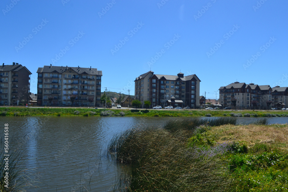 a river and some green areas near an urbanization of buildings and houses