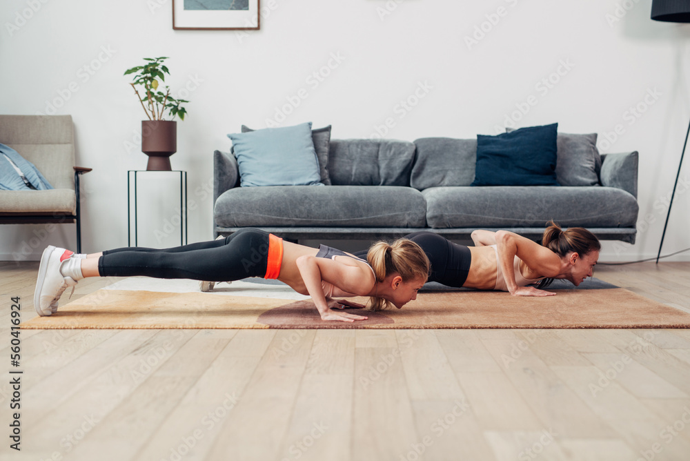 Push-ups. Mother and daughter working out at home.