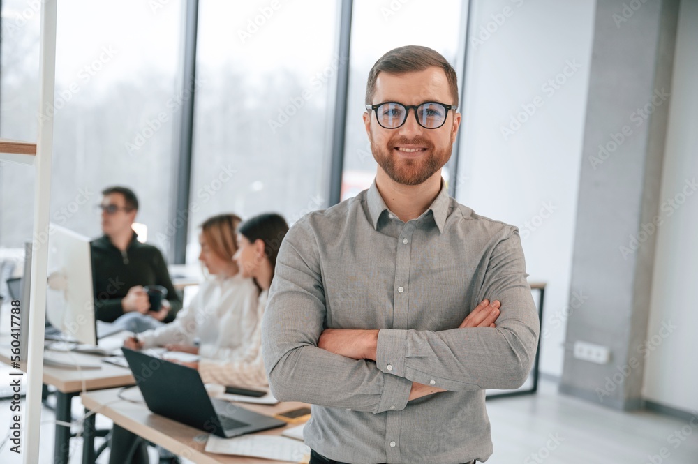 Obraz premium Man is standing with arms crossed. Successful team are working together in the office. Conception of business
