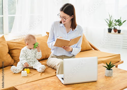 Successful young mother with newborn baby working in online conference mode.