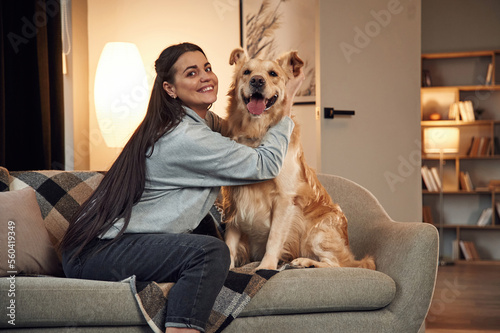 Playing and sitting on the sofa. Woman is with golden retriever dog at home