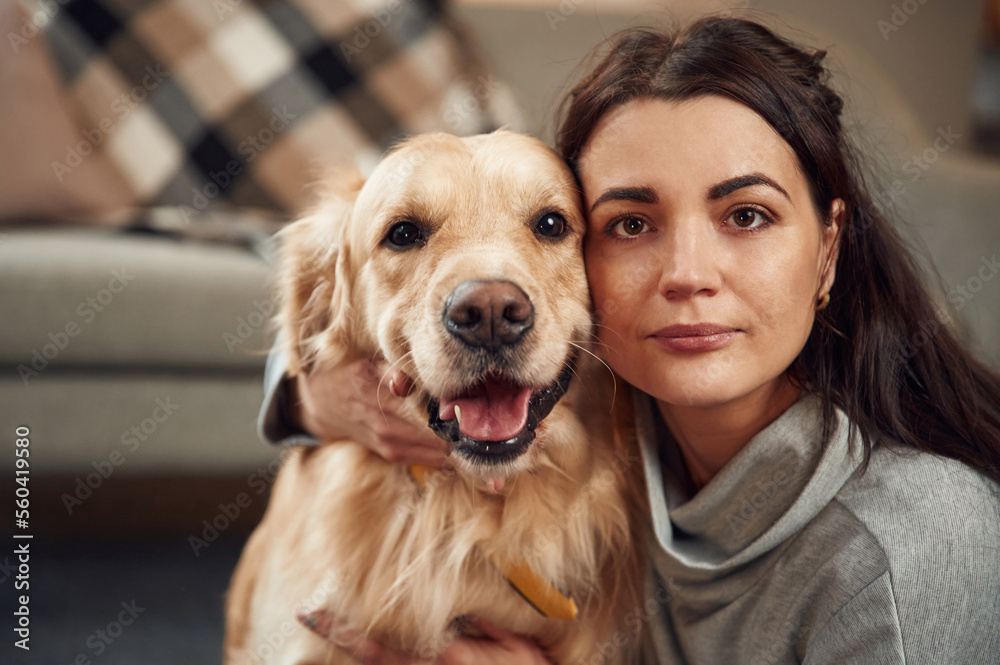 Looking at the camera. Woman is with golden retriever dog at home Looking at the camera. Woman is with golden retriever dog at home