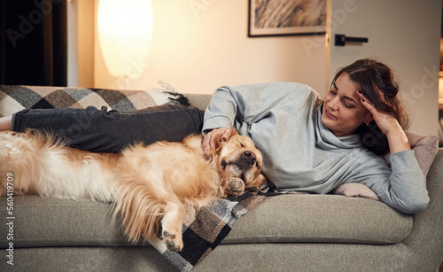 Lying down on the sofa together. Woman is with golden retriever dog at home © standret