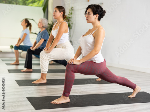 Portrait of young sporty girl having yoga class with group at healthy sports club