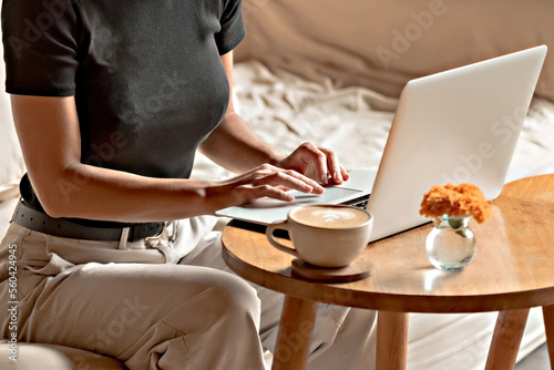 Woman with a cup of coffee working at laptop face unrecognized