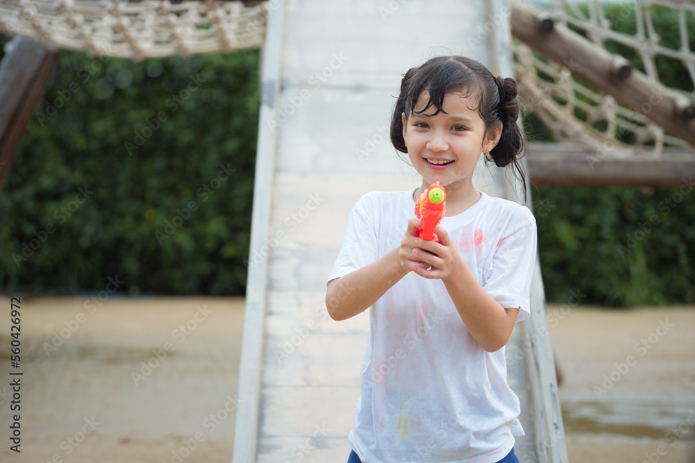 Happy child girl has fun playing sliding and shooting water gun on outdoor playground on hot summer day outdoors. Happy child girl has fun playing sliding and shooting water gun on outdoor playground on hot summer day outdoors.