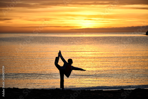 silhouette of a person doing yoga on a beach at sunrise or sunset
