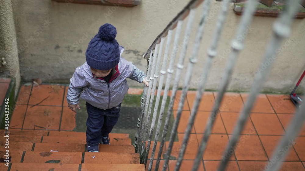 Toddler boy going up the stairs. Baby child goes up the stair during winter season Toddler boy going up the stairs. Baby child goes up the stair during winter season