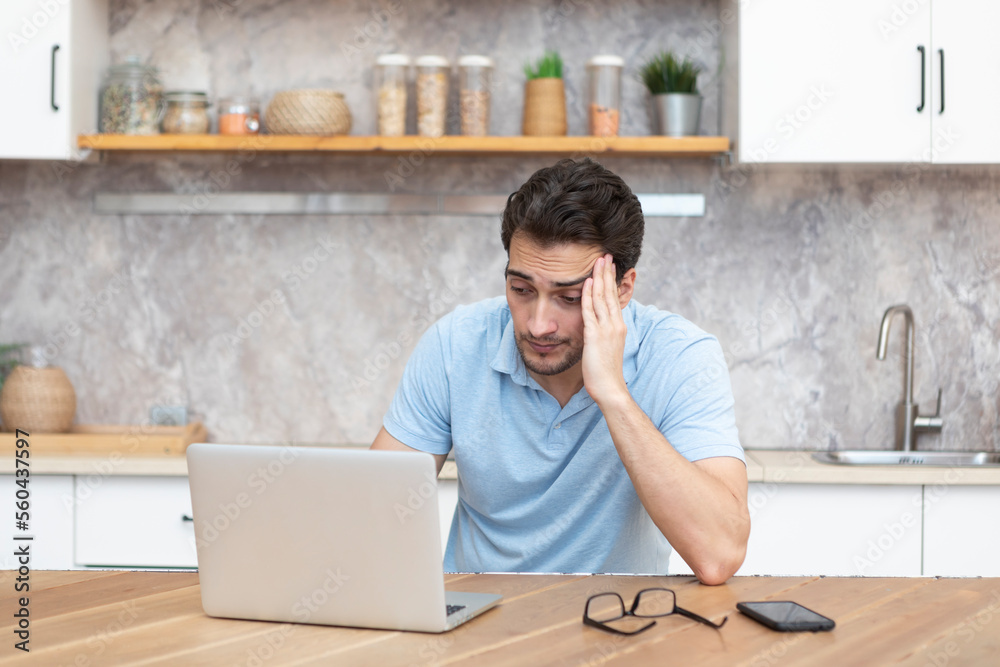 Stressed man working on laptop in the kitchen at home. Distance work concept Stressed man working on laptop in the kitchen at home. Distance work concept