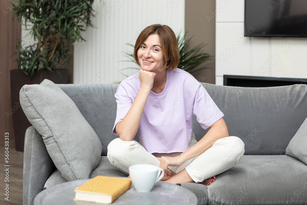 Young attractive woman sitting on the couch and reading book at home Young attractive woman sitting on the couch and reading book at home