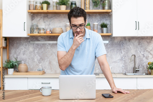 Young handsome man working on laptop at home. Distance work and online education concept 