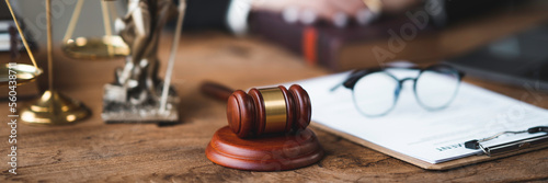 Professional Asian female lawyer or legal advisor sitting at her desk holding hands on books on justice concept Sections in the law that govern the conduct.