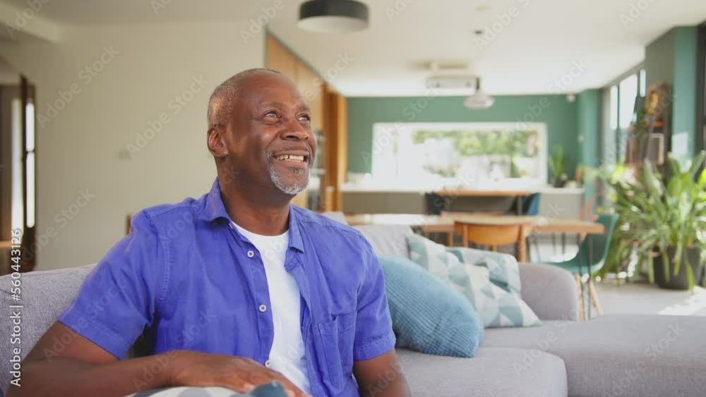 Portrait of senior man sitting on sofa in stylish lounge dining room smiling and laughing - shot in slow motion Portrait of senior man sitting on sofa in stylish lounge dining room smiling and laughing - shot in slow motion