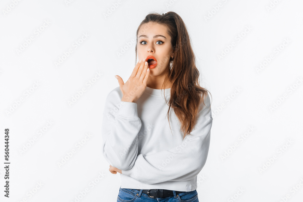 Ouch. Amazed young woman showing Oops expression at the camera. Portrait of young girl with long hair, arm cover mouth, standing against white studio background Ouch. Amazed young woman showing Oops expression at the camera. Portrait of young girl with long hair, arm cover mouth, standing against white studio background