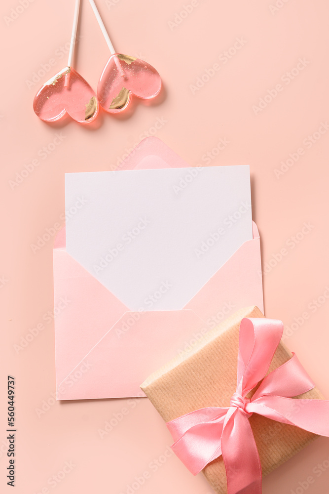 Valentine's card with blank for love letter, pink envelope, gift, lollipops as heart on pink background. View from above. Copy space. Vertical format. Valentine's card with blank for love letter, pink envelope, gift, lollipops as heart on pink background. View from above. Copy space. Vertical format.