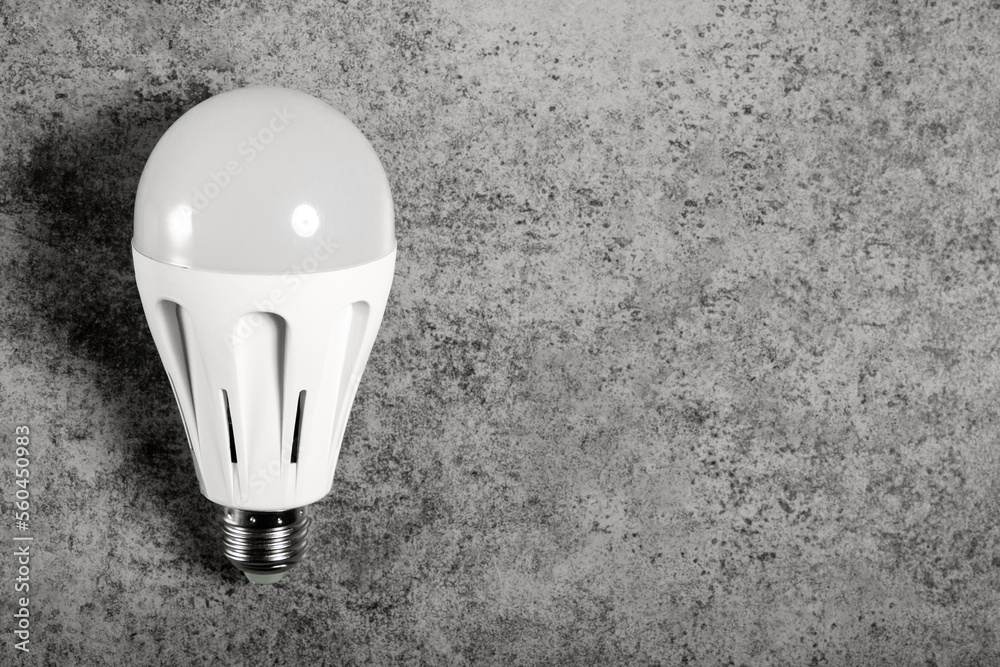 LED energy-saving lamp with E27 screw cap base on gray background with copy space. LED energy-saving lamp with E27 screw cap base on gray background with copy space.