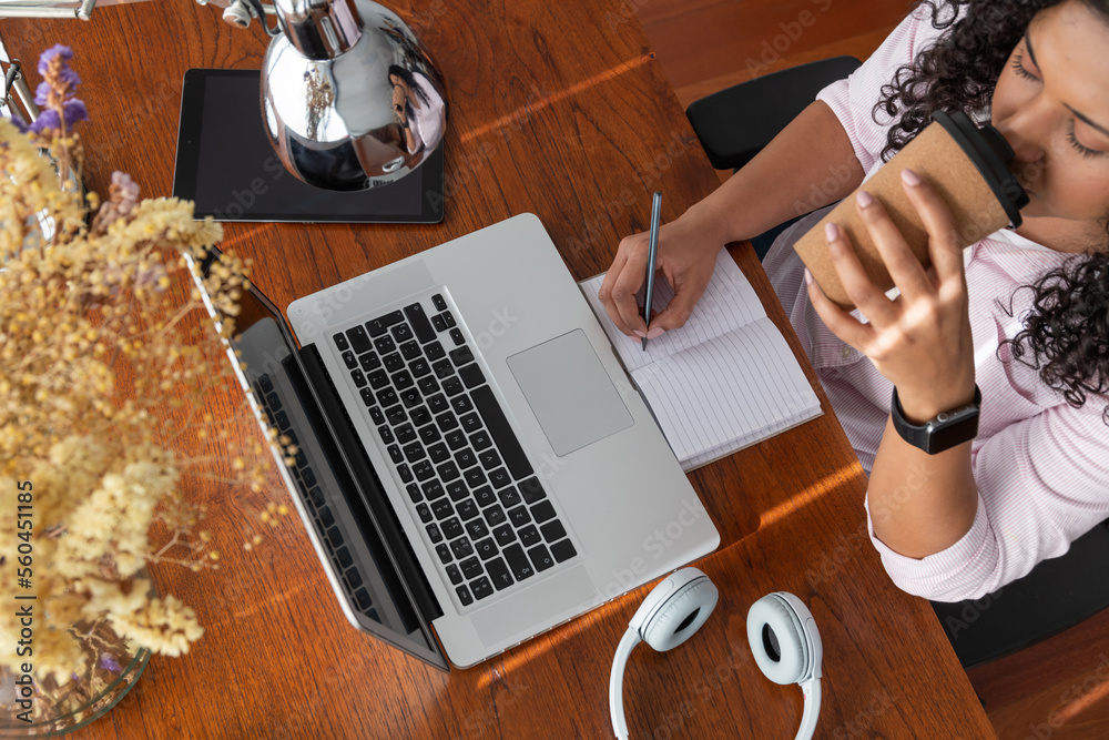 © ADDICTIVE STOCK - Woman taking notes while drinking coffee
