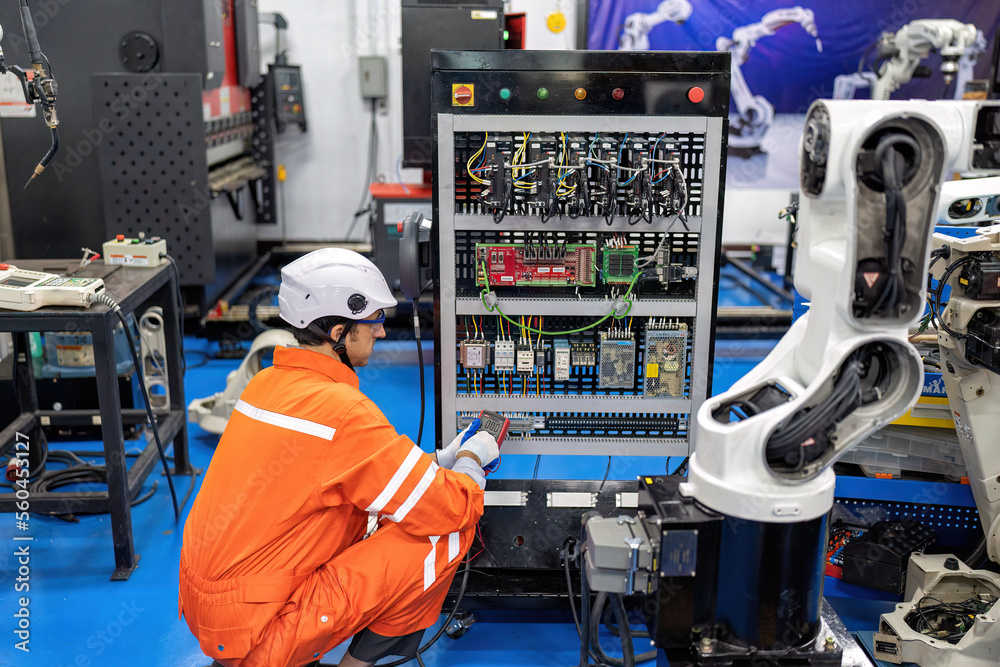 Robot Testing Electronics Engineer hold multimeter testing cable wiring robotic control panel at ...