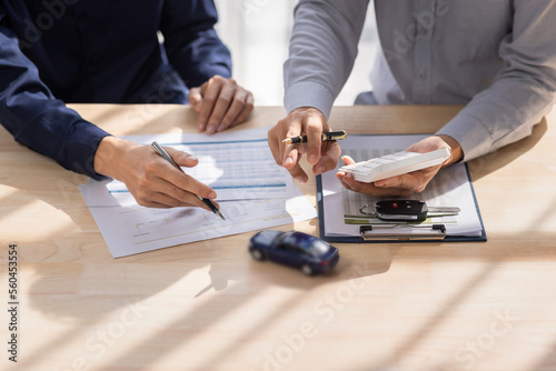 Car Insurance document or lease concept the car broker assisting his customer and explaining the detail of the car contact.  Car key Buying or selling signing .