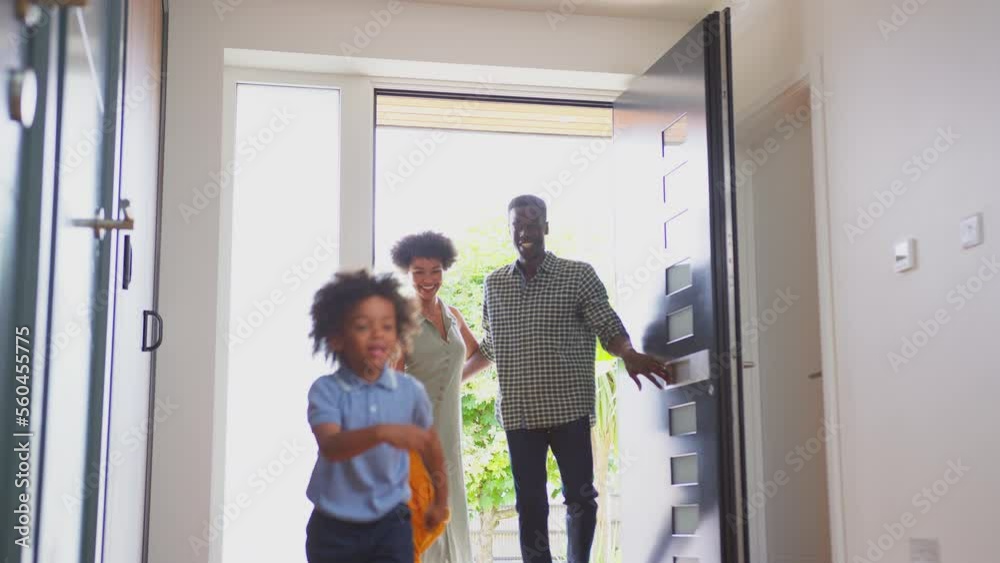 Excited children running through front door into hallway of house with parents behind as family return from trip out - shot in slow motion