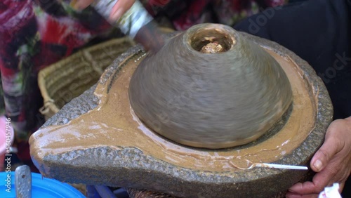 Berber Woman Grinds Argan Almonds in Stone Hand Mill Making Argan Oil in Morocco