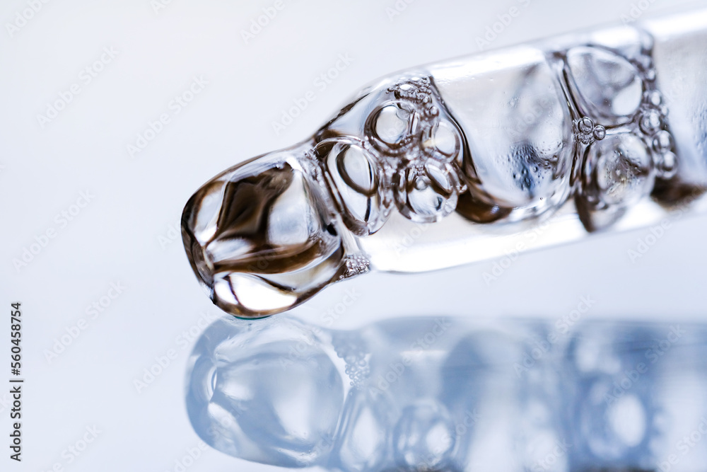 Cosmetic liquid and glass pipette close-up. Macrophotograph, side view. Cosmetic liquid and glass pipette close-up. Macrophotograph, side view.