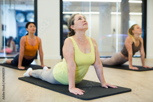 Women of different ages in upward-facing dog pose during yoga group training