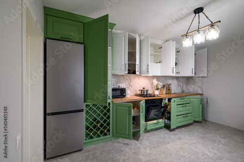 Doors open and drawers pulled out at new green and white kitchen furniture