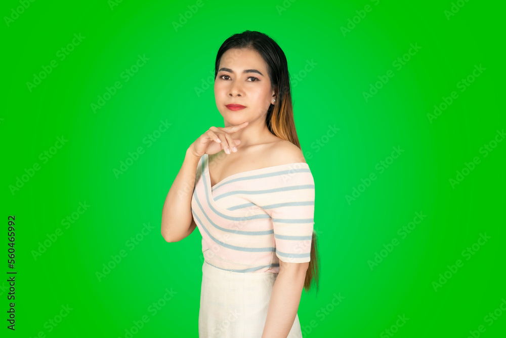 A beautiful woman stands on her side and puts her index finger under her chin A beautiful woman stands on her side and puts her index finger under her chin
