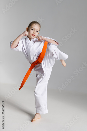 Little girl learns karate techniques on a white background, sport hobby.