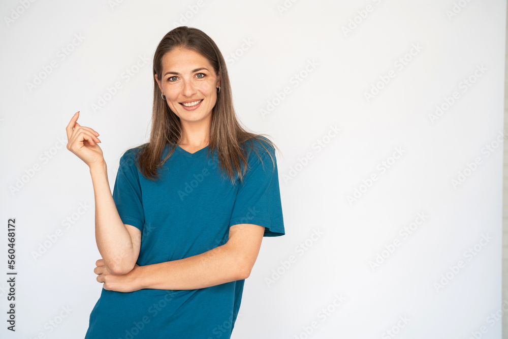 Portrait of joyful young woman. Female Caucasian model with brown hair and grey eyes in turquoise T-shirt and casual jeans smiling standing aside. Lifestyle concept Portrait of joyful young woman. Female Caucasian model with brown hair and grey eyes in turquoise T-shirt and casual jeans smiling standing aside. Lifestyle concept