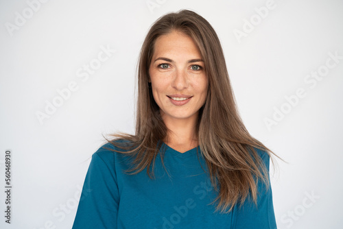 Portrait of charming young woman. Female Caucasian model with brown hair and grey eyes in turquoise T-shirt and casual blue jeans smiling looking at camera. Lifestyle concept