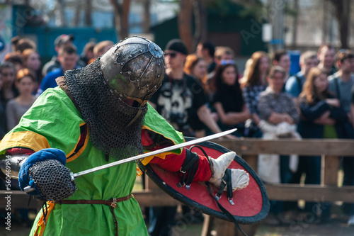 Medieval restorers fight with swords in armor at a knightly tournament, historical restoration of knightly fights © olinchuk