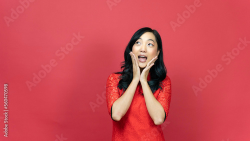 Young woman wearing traditional cheongsam qipao dress posing wow action isolated on red background. Happy Chinese new year