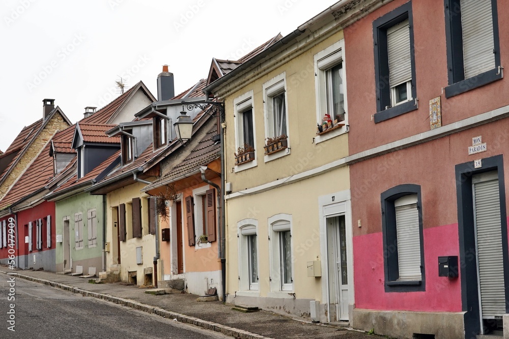 Street in residential part of the town with traditional French architecture. The houses are painted in various colors. Above the entrance door of the nearest one there is written in French my paradise