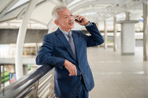 Asian senior mature middle aged businessman using smartphone in modern city