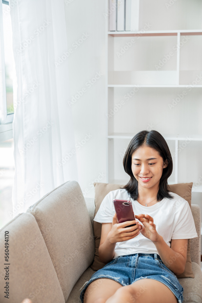 Asian Woman using cell phone sitting on couch. Asian Woman using cell phone sitting on couch.