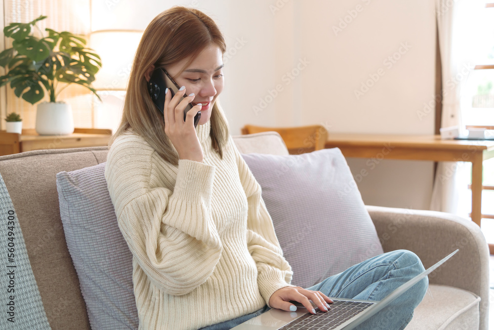 Asian woman using mobile phone on sofa at living room. .Start up small business owner. Asian woman using mobile phone on sofa at living room. .Start up small business owner.