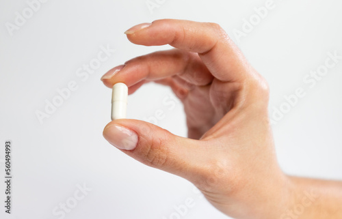 Hand holding a tablet on a white background, supplementation and health, physical and mental health concept