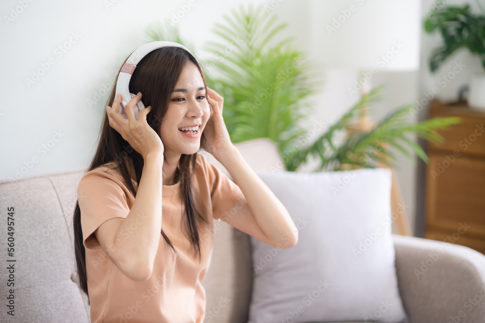 Young asian woman with headphones relaxing at home. listening to music. man sitting on cozy sofa wearing headphone Young asian woman with headphones relaxing at home. listening to music. man sitting on cozy sofa wearing headphone