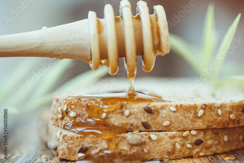 Close-up of a honey drizzler dripping honey on a slice of seeded brown toast photo